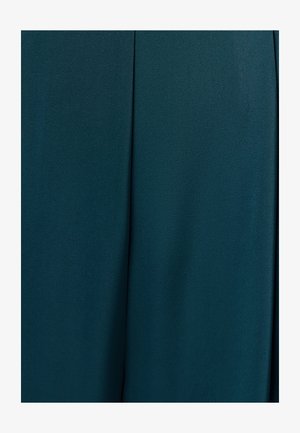 Tumši teal audums ar gludu tekstūru un izteiktu vertikālu šuvi, kas iet caur centru.