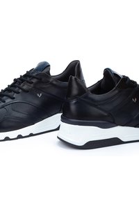 Black leather sports shoes with a smooth texture, white sole, and minimalistic design; features contrasting blue accents and lace-up front.