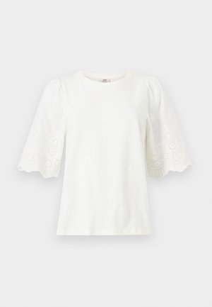 Fehér blúz kerek nyakkivágással és könyökig érő puffos ujjakkal, amelyek apró virágmintás lyukacsos mintákat és hullámos szegélyeket tartalmaznak.