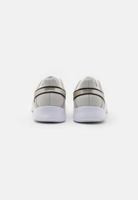 Gray athletic shoes with a textile upper, padded collar, and a flexible white sole. Features a black and gold accent band across the heel.