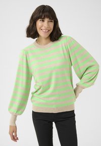 Maglione beige chiaro con strisce orizzontali verde brillante, caratterizzato da maniche a sbuffo e un collo a costine. Abbinato a pantaloni neri.
