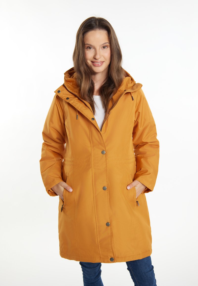 Parka gialla senape resistente all'acqua con cappuccio, bottoni a pressione frontali, tasche laterali e una vestibilità rilassata. Tessuto morbido con una superficie liscia.