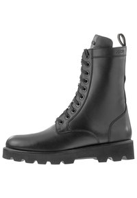 Las botas de combate de cuero negro cuentan con una suela robusta y texturizada, ojales reforzados y una cinta en el talón para facilitar su uso.