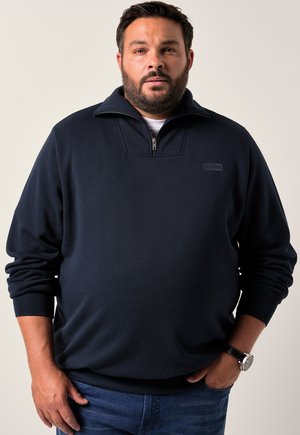 Marineblå halv-zip sweatshirt med en mock krave, lange ærmer og en lille logo detalje på brystet. Fremstillet af et blødt stof.