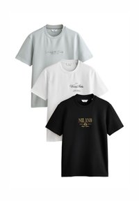 Három rövid ujjú póló egymáson: halvány zöld, fehér és fekete. Mindegyiken ellentétes színű felirat található, a fekete pólón arany betűkkel.