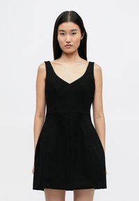 Μαύρο αμάνικο φόρεμα με V-λαιμόκοψη και εφαρμοστό μπούστο. Άνοιγμα φούστας με δύο πλαϊνές τσέπες, κατασκευασμένο από μια λεία, υφασμάτινη ύφανση.