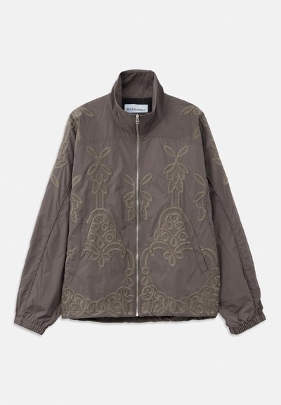 Brown embroidered jacket with a high collar, featuring intricate floral and swirling patterns. It has a front zipper and elastic cuffs.