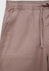 Short en tissu couleur mauve avec taille élastique, cordon et deux poches avant visibles.