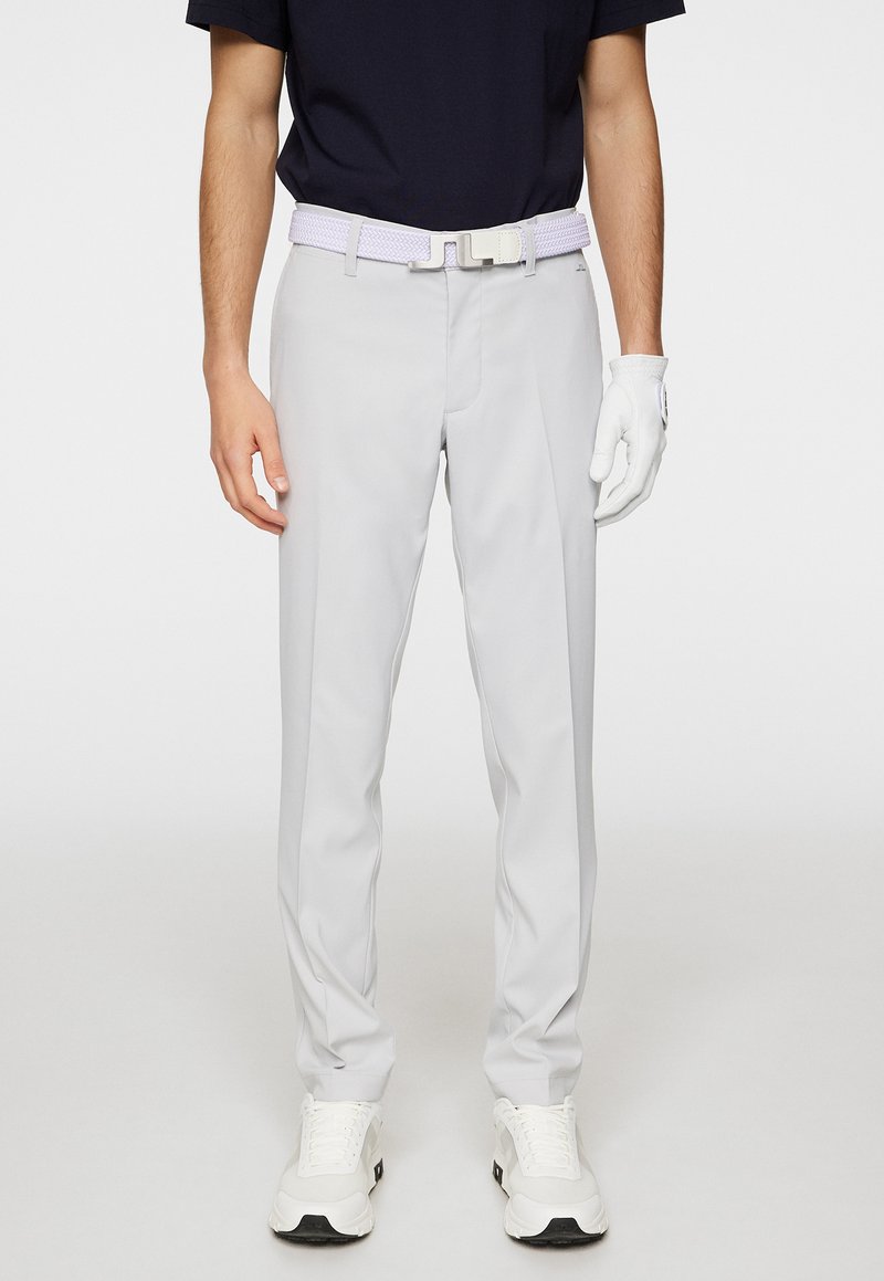 Vaaleanharmaat golfsaksit, joissa on sileä pinta, muototettu malli ja huomaamattomat taskut. Yhdistettynä valkoiseen punottuun vyöhön ja valkoiseen hanskaan.