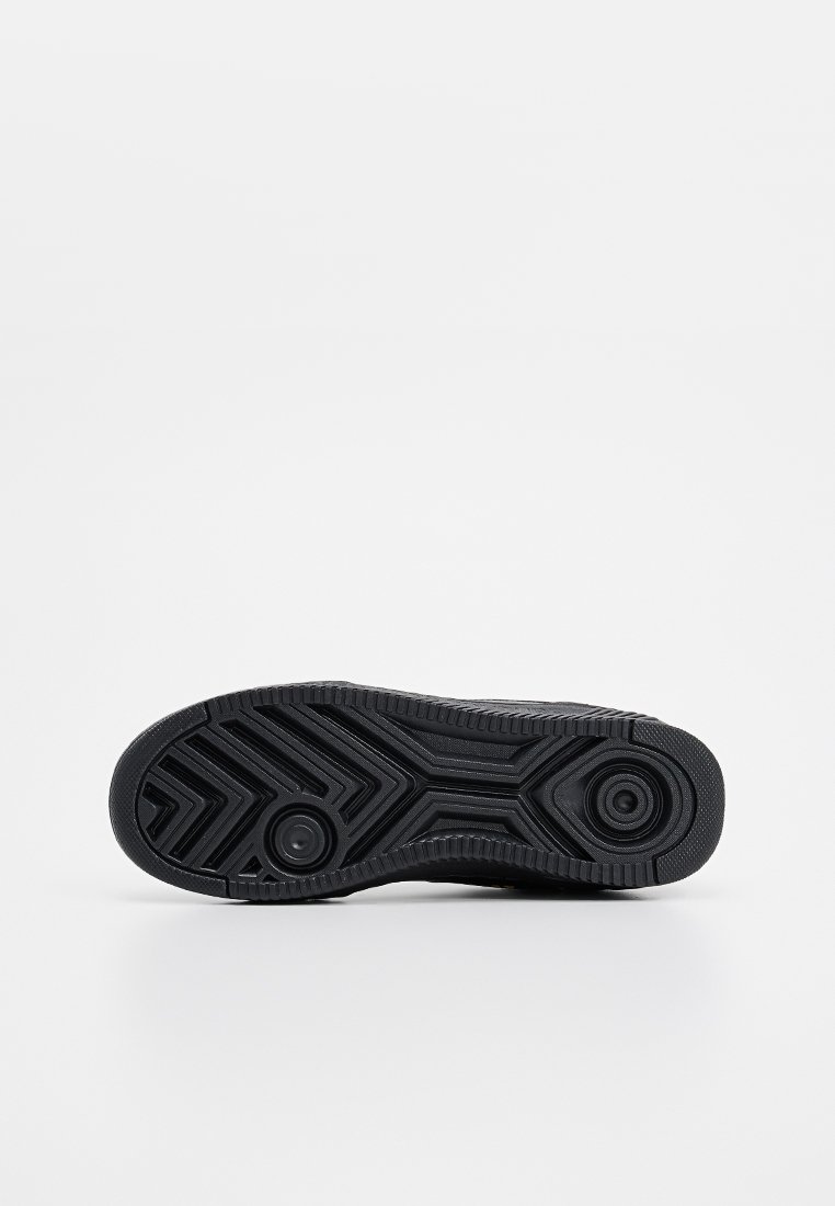 Suela de zapato deportivo negro con una superficie de goma texturizada que presenta patrones en zigzag y acentos circulares para el agarre.