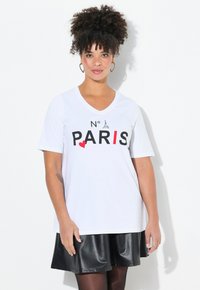 Bílý krátký rukáv T-shirt s výstřihem do V, s černým a červeným nápisem "N° PARIS" a malou grafikou Eiffelovy věže. Měkká bavlněná tkanina.