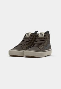 Høye sneakers i mørkebrun kanvas med hvite detaljer, forsterkede sømmer og gummisåle. Har en klassisk logo på tungen.