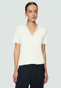 Witte korte mouw V-hals T-shirt van zachte stof, met een relaxte pasvorm en een gladde textuur, gecombineerd met donkere broek.