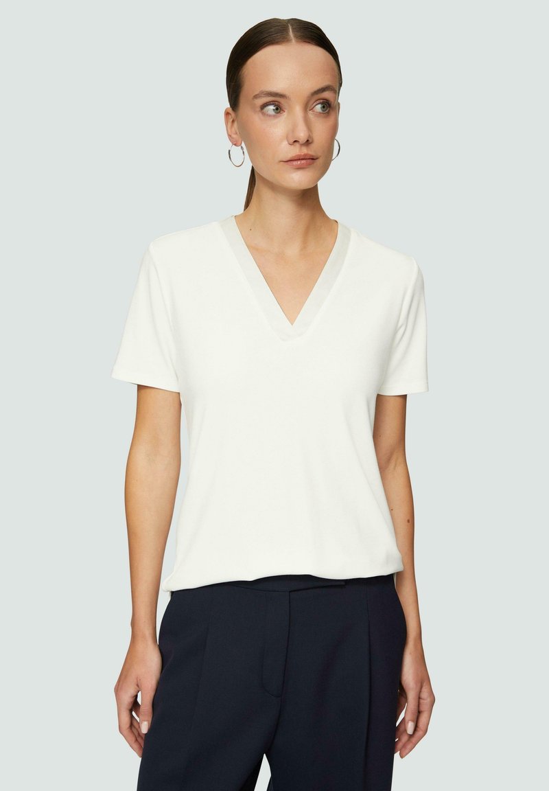 Witte korte mouw V-hals T-shirt van zachte stof, met een relaxte pasvorm en een gladde textuur, gecombineerd met donkere broek.
