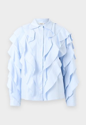 Svijetloplava bluza s dugim rukavima i naboranim slojevima sprijeda, na rukavima i ovratniku, s kopčanjem na gumbe sprijeda i klasičnim ovratnikom.