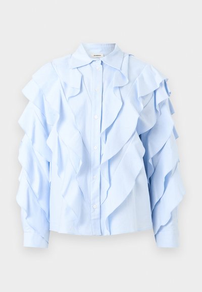 Ανοιχτό μπλε πουκάμισο με μακριά μανίκια και στρώσεις βολάν μπροστά, στα μανίκια και στον γιακά, με κουμπιά μπροστά και κλασικό γιακά.