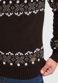 Dunkelbrauner Pullover mit weißen und grauen Schneeflockenmuster. Gerippte Textur und Bündchen, mit einem kleinen Lederetikett mit der Aufschrift "ISOLID."