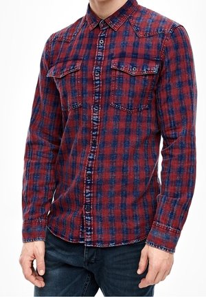 Camisa de franela a cuadros rojos y azules con botones en la parte delantera, dos bolsillos en el pecho, mangas largas y una textura ligeramente deslavada.