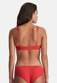 Red bra with a textured pattern, adjustable straps with floral accents, and a hook-and-eye closure at the back. Matching red briefs.