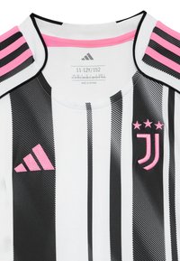 Maillot de la Juventus avec des rayures verticales noires et blanches. Présente des accents roses sur le col et l'épaule. Tissu texturé avec des logos.