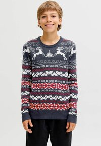 Kötött pulóver, sötétkék alap színnel, fehér és piros ünnepi mintákkal, köztük rénszarvasok, hópehely és geometriai minták, bordás mandzsettákkal.