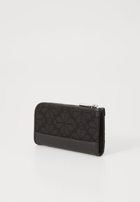 Black wallet featuring a textured fabric with floral pattern and smooth leather accents. Zipper closure at the top, compact rectangular shape.