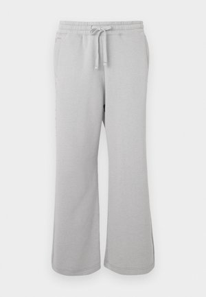 Pantaloni da ginnastica grigi chiari realizzati in materiale morbido, con un design a gamba larga, vita elastica con cordino e tasche laterali.