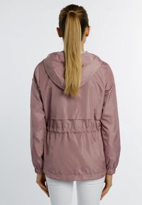 Jasnoróżowa kurtka z kapturem wykonana z gładkiego, lekkiego materiału, z elastycznym pasem i mankietami, charakteryzująca się prostym wzornictwem i brakiem widocznych wzorów.
