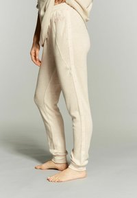 Beige joggerbroeken van zacht materiaal, met een taps toelopende pasvorm, elastische tailleband en lichtroze zijkanten met logo-detail.