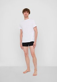 Vit bomull t-shirt med korta ärmar, kombinerad med svarta korta underkläder. Passformen är avslappnad och tyget ser slätt ut.