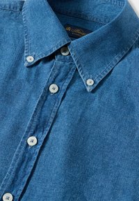 Camicia di jeans bottonata in azzurro chiaro, caratterizzata da un colletto a punta, bottoni bianchi e dettagli di texture sottili. Tessuto morbido con un design casual.