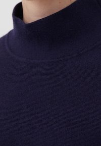 Pull col montant bleu marine en tissu tricoté. Présente une texture lisse et un col côtelé, avec une silhouette ajustée et un design minimaliste.
