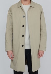Beige trenchcoat med krage, långa ärmar och sex svarta knappar. Tyget ser slätt ut, med sidofickor och en avslappnad passform.