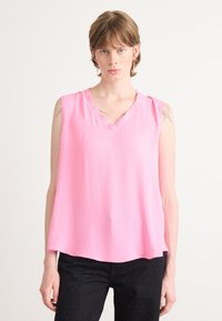 Mouwloze roze top met een V-halsontwerp, gemaakt van lichte stof. Heeft een losse pasvorm en subtiele draping voor comfort.