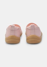 Zapatos de lona rosa sin cordones con un upper texturizado, forma redondeada y diseño minimalista. Forro interior suave y suela de goma de color beige claro.