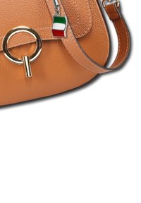 Tan leren handtas met gouden ronde sluiting en een kleine charme met de kleuren van de Italiaanse vlag die aan de band hangt.