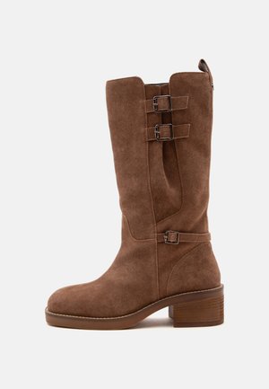 Botte mi-mollet en daim marron avec trois boucles réglables, bout arrondi, petit talon empilé et languette à l'arrière.