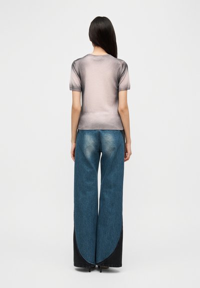 Ελαφρύ πλεκτό τοπ με διαβαθμισμένο χρώμα και κοντά μανίκια, σε συνδυασμό με φαρδιά μπλε τζιν παντελόνια με σχισμή στο τελείωμα και ξεθωριασμένες λεπτομέρειες.