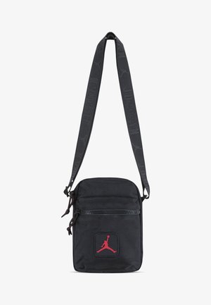 Borsa a tracolla nera in nylon con tracolla regolabile, chiusure a zip e logo Jordan rosso sul fronte. Superficie texturizzata, design compatto.