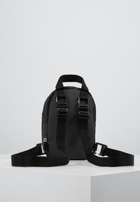 Svart ryggsäck med justerbara remmar, tillverkad av slitstarkt material, med en texturerad design och dubbla bärhandtag.