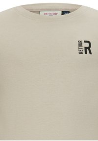 Helles beige T-Shirt mit kurzen Ärmeln aus weicher Baumwolle. Mit rundem Ausschnitt und einem aufgedruckten schwarzen Logo "RETOUR R" auf der Brust.