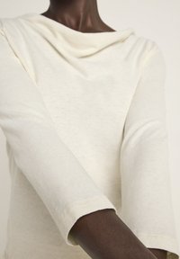 Off-White, langärmliges Oberteil mit drapiertem Kragen, weicher Textur und eng anliegendem Ärmeln. Minimalistisches Design ohne sichtbare Muster oder Beschläge.