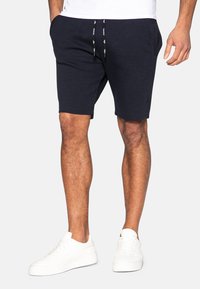 Mørkeblå bomuldsshorts med elastisk talje og snøre. Har sidelommer og en afslappet pasform, som slutter lige over knæet.