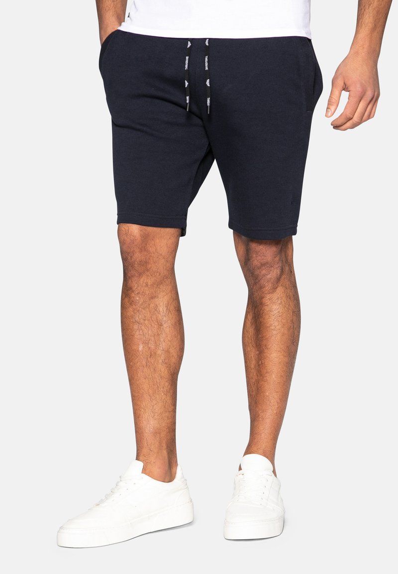 Mørkeblå bomuldsshorts med elastisk talje og snøre. Har sidelommer og en afslappet pasform, som slutter lige over knæet.