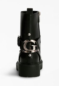 Bottine en cuir noir à bout rond, avec des garnitures en argent et une fermeture éclair sur le côté. Elle est dotée d'une sangle décorative fixée par une boucle avec logo.