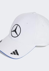 Witte honkbalpet met een zwart geborduurd Mercedes-logo aan de voorkant en zwarte Adidas-strepen aan de zijkant. Blauwe accenten op de rand.