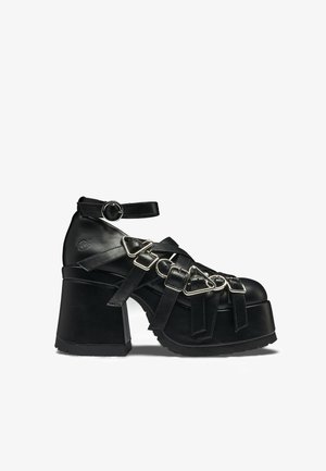 Μαύρο χοντρό παπούτσι πλατφόρμα με πολλαπλά δερμάτινα λουριά και ασημένιες αγκράφες, λουράκι αστραγάλου με στρογγυλή αγκράφα και χοντρό τακούνι.