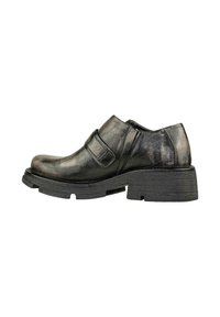 Scarpa in pelle nera con punta rotonda, a taglio basso e una cinturino in velcro. Presenta una superficie testurizzata e una suola in gomma spessa.