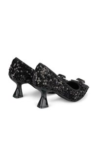 Scarpe con tacco nere coperte di paillettes, con punte arrotondate e tacchi a forma di tromba unici. Due fibbie decorative sul davanti.
