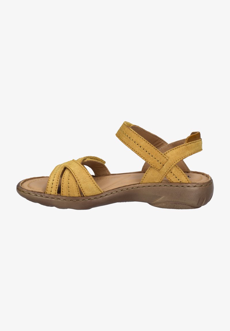 Sandale en daim jaune avec un design de brides croisées, une semelle intérieure rembourrée et une semelle en caoutchouc flexible et texturée. Talon bas pour le confort.